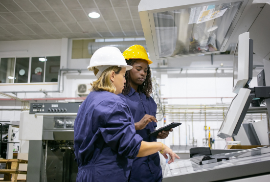 Two people wearing hardhats in a factory.